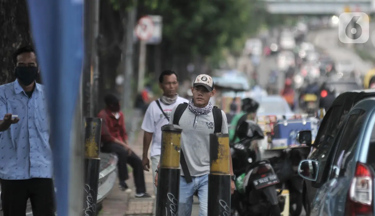 Pejalan kaki tanpa mengenakan masker saat melintas di kawasan Cawang, Jakarta, Rabu (8/4/2020). Organisasi Kesehatan Dunia (WHO) telah merekomendasikan agar siapa saja menggunakan masker saat berada di tempat umum demi memutus mata rantai penyebaran virus Corona. (merdeka.com/Iqbal Nugroho)