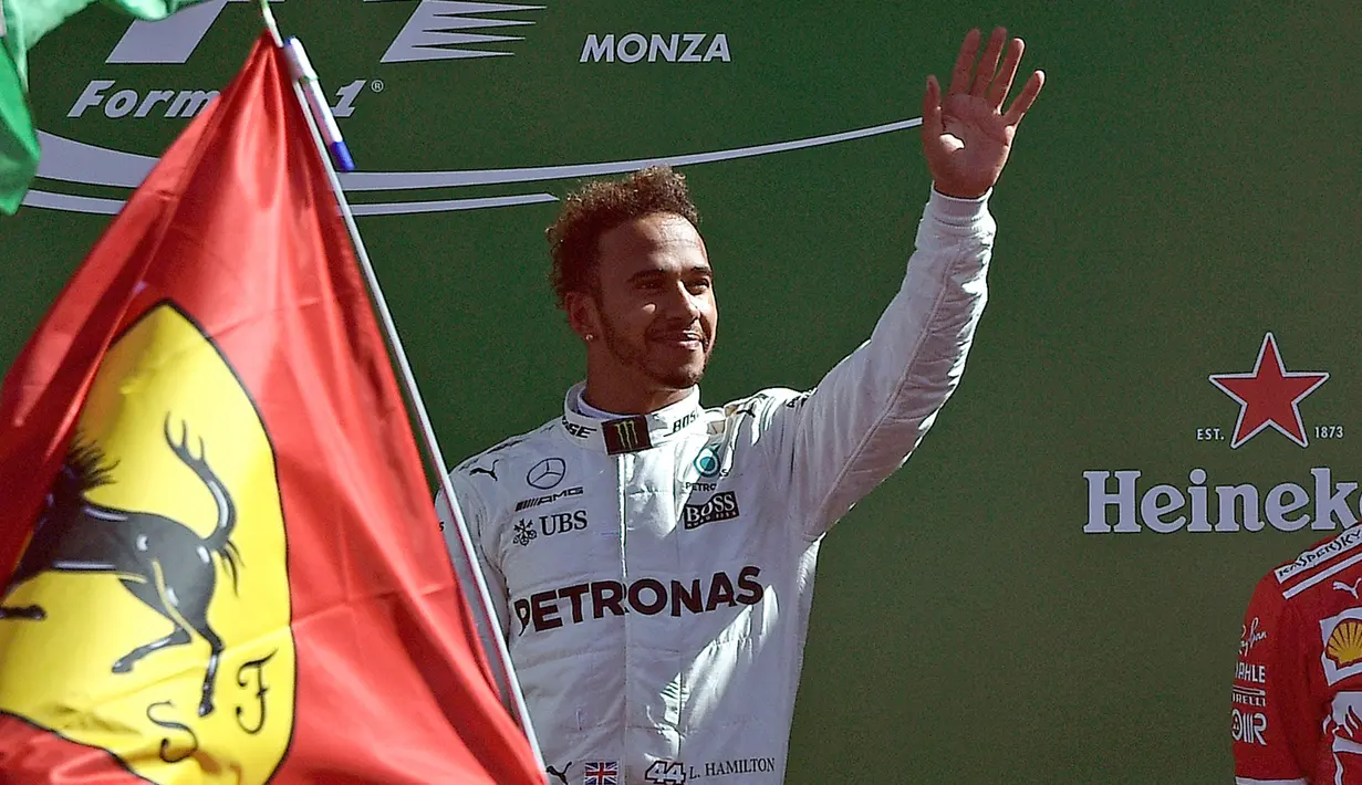 Pembalap Mercedes Lewis Hamilton merayakan kemenangannya di atas podium usai memenangkan balapan F1 GP Italia, di arena Monza, Italia (3/9). (AFP Photo/Miguel Medina)
