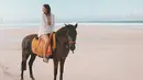 Berhasil memotret keindahan pantai dan langit yang luar biasa, Pamela Bowie berpose di atas kuda dengan robe dan celana pendek putih. Foto: Instagram.