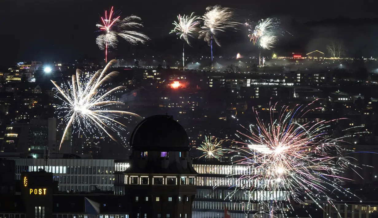 Kembang api menerangi langit di atas Zurich dengan pemandangan Danau Zurich, Swiss, saat perayaan Malam Tahun Baru pada Senin (1/1/2024) dini hari. (Ennio Leanza/Keystone via AP)