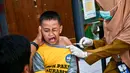 Seorang murid bereaksi saat menerima vaksin difteri di sebuah sekolah dasar di Surabaya pada Selasa 4 November 2025. Melalui kegiatan ini, pemerintah berupaya memastikan anak-anak terlindungi dari penyakit menular yang dapat dicegah melalui imunisasi, sekaligus menjaga kekebalan komunal di lingkungan sekolah. (Juni KRISWANTO/AFP)