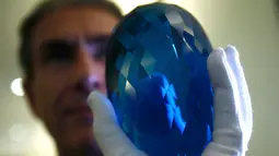 Pengusaha Inggris dan filantropis Maurice Ostro memperlihatkan batu topaz miliknya, Inggris, Selasa (27/9). Batu topaz terbesar di dunia ini memiliki berat 2 kg. (REUTERS / Peter Nicholls)