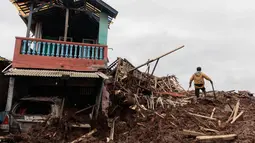 Tim pencari dan penyelamat gabungan mengerahkan tambahan alat berat untuk memperluas area pencarian. Tampak dalam foto, seorang pria berdiri di dekat reruntuhan rumah saat tim penyelamat mencari korban yang terkubur longsor di Desa Pasirlangu, Cisarua, Kabupaten Bandung, Jawa Barat, pada 26 Januari 2026. (Aditya Aji/AFP)