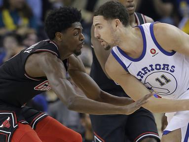 Pemain Warriors, Klay Thompson (kanan) mencoba melewati adangan pemain Chicago Bulls, Justin Holiday pada laga NBA basketball game di Oracle Arena, Oakland, (24/11/2017). Warriors menang 143-94. (AP/Jeff Chiu)