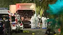 Polisi dan ahli forensik berdiri disamping sebuah truk yang menabrak kerumunan orang yang tengah menyaksikan festival di Nice, Prancis, Kamis (14/7). Sedikitnya 60 orang tewas dan ratusan lainnya luka akibat hantaman truk tersebut. (REUTERS/Eric Gaillard)