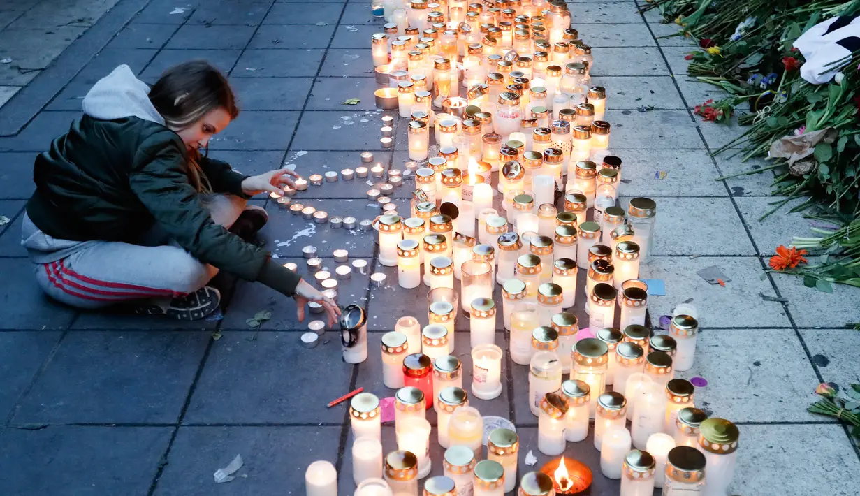 Seorang wanita menyalakan lilin di lokasi terjadinya serangan truk di Stockholm, Swedia, Minggu (9/4). Sebuah truk yang dibajak menabrakkan diri ke kerumunan pejalan kaki pada Sabtu (8/4) dan menewaskan empat orang. (AP Photo / Markus Schreiber)