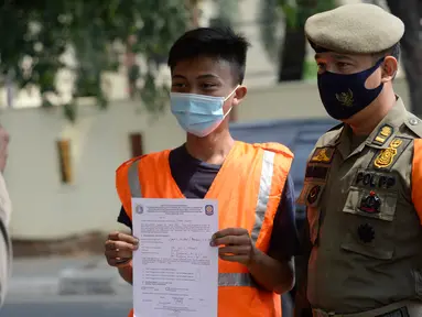 Petugas Satpol PP memberikan sanksi sosial kepada warga pelanggar karena tidak menggunakan masker saat melintas di Lebak Bulus, Jakarta, senin (14/9/2020). Pemerintah Provinsi DKI Jakarta memperketat kembali PSBB karena kasus Covid-19 terus mengalami peningkatan. (merdeka.com/Dwi Narwoko)