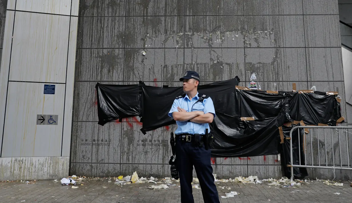 Polisi berjaga di pintu masuk utama kantor polisi yang dirusak di Hong Kong, Sabtu (22/6/2019). Markas polisi tersebut digeruduk ribuan demonstran yang menuntut pembebasan massa yang ditangkap dalam aksi menolak RUU Ekstradisi. (AP Photo/Vincent Yu)