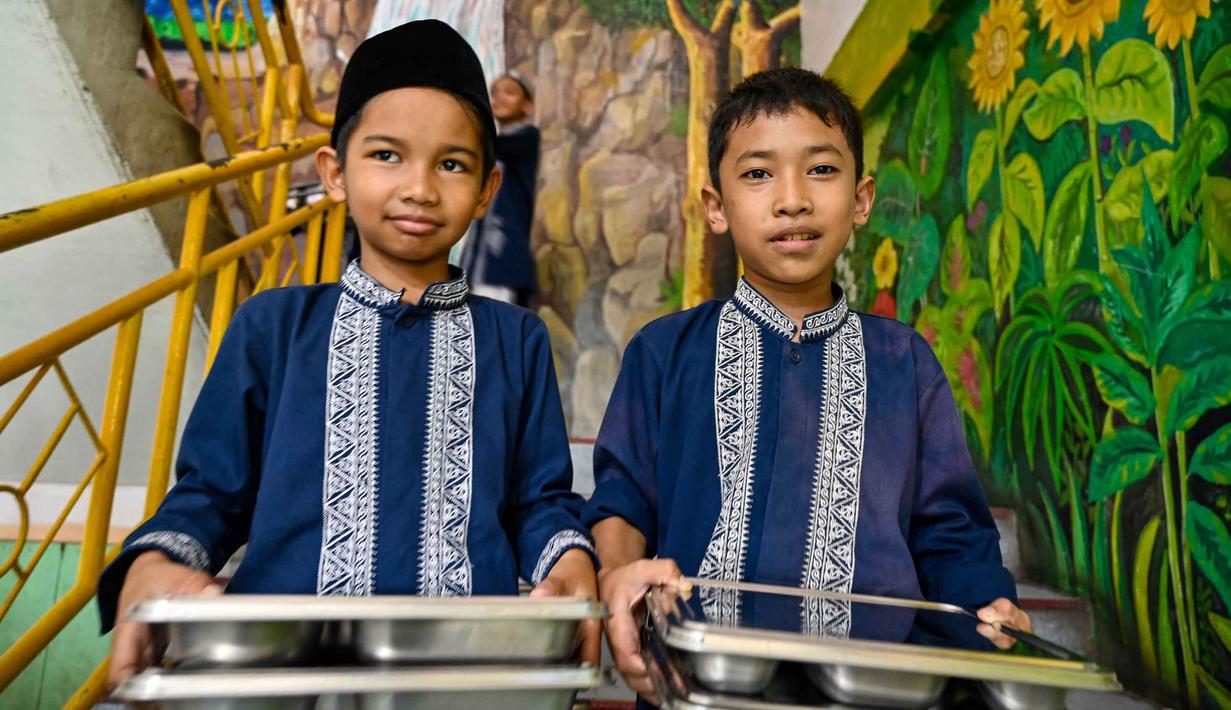 Para siswa membawa makanan yang dipasok oleh program Makan Bergizi Gratis (MBG) di sebuah sekolah dasar di Banda Aceh pada Kamis 30 Oktober 2025. (CHAIDEER MAHYUDDIN/AFP)