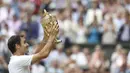 Petenis Swiss, Roger Federer, mengangkat trofi usai memastikan gelar juara dengan mengalahkan petenis Kroasia, Marin Cilic pada laga final Wimbledon 2017 di London, Minggu (16/7/2017). Federer menang 6-3, 6-1, 6-4 atas Cilic. (AFP/Daniel Leal-Olivas)