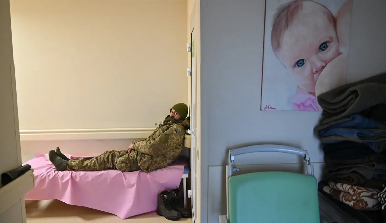 Seorang prajurit Ukraina yang terluka ringan beristirahat di klinik bersalin swasta Leleka ('Stork') yang terletak tidak jauh dari desa garis depan Horenka, Kiev pada 10 Maret 2022. Klinik tersebut menjadi stasiun bantuan garis depan untuk tentara dan warga sipil yang terluka. (Sergei SUPINSKY/AFP)
