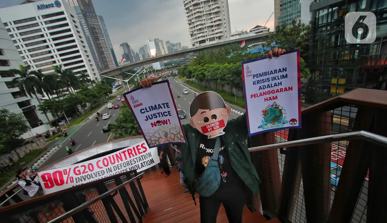 Sejumlah aktivis yang tergabung dalam Extintion Rebellion (XR) dan Walhi Jakarta melakukan aksi di JPO Pinisi, Jalan Jenderal Sudirman, Jakarta, Senin (14/11/2022). Aksi tersebut dilakukan untuk menyerukan kepada para pemimpin agar menghentikan “pencucian hijau” dan praktik ekonomi “business-as-usual” yang secara sistematis memperburuk krisis iklim dan mendorong umat manusia pada kehancuran ekologis & kepunahan massal. Negara-negara G20 turut menyumbang atas 80 persen emisi karbon dunia dan 60 persen populasi penduduk bumi. (Liputan6.com/Angga Yuniar)