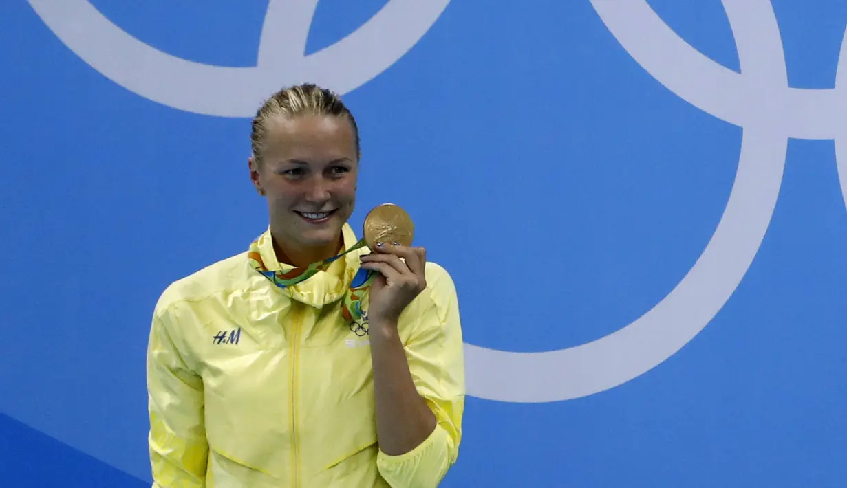 Senyum bahagia perenang Swedia Sarah Sjostrom di podium dengan medali emas renang nomor 100 meter gaya kupu-kupu yang diraihnya pada Olimpiade 2016 di Rio de Janeiro, Minggu (7/8). Sjostrom memecahkan rekor dunianya atas namanya sendiri (Odd Andersen/AFP)