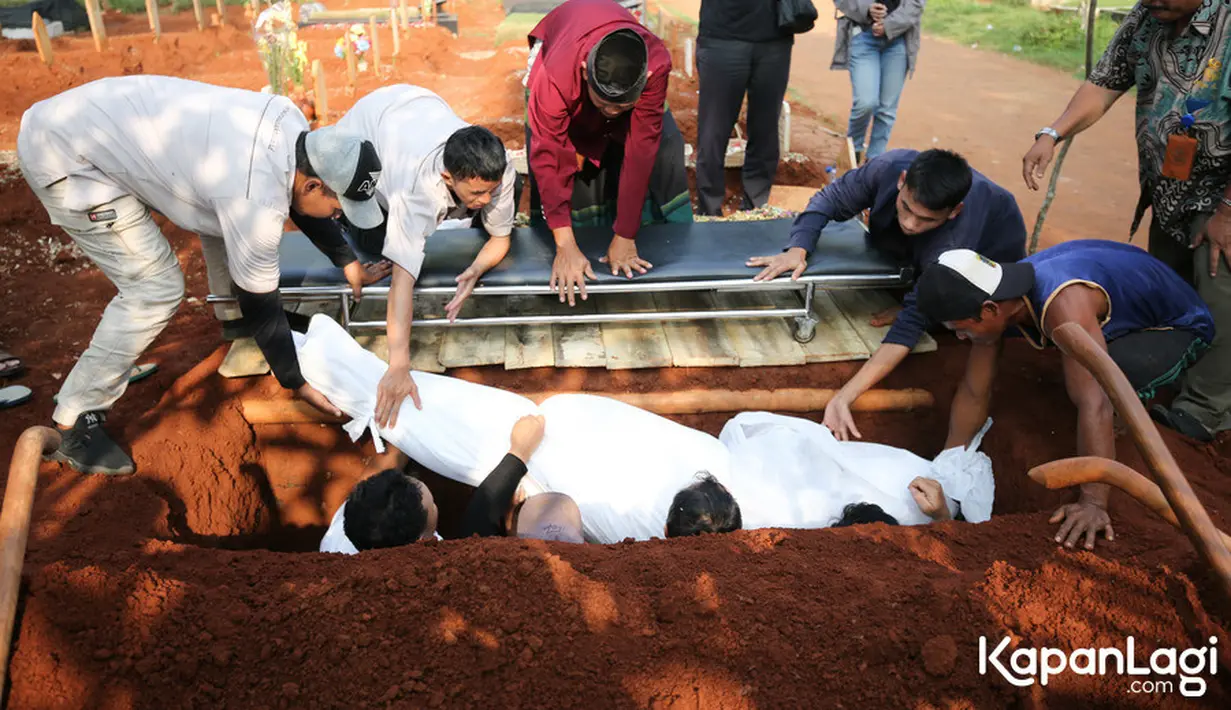 Jenazah chef Haryo diturunkan ke liang lahat. Tampak anak mendiang juga ikut masuk ke dalam liang untuk membantu proses pemakaman sang ayah. [Foto: KapanLagi.com®/Bayu Herdianto]