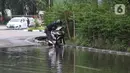 Pengendara memanfaatkan genangan air untuk mencuci kendaraan di Jalan HBR Motik Kemayoran, Jakarta, Selasa (25/2/2020). Hujan yang mengguyur Jakarta sejak Senin (24/2) malam membuat sejumlah kali meluap dan menyebabkan banjir. (Liputan6.com/Helmi Fithriansyah)