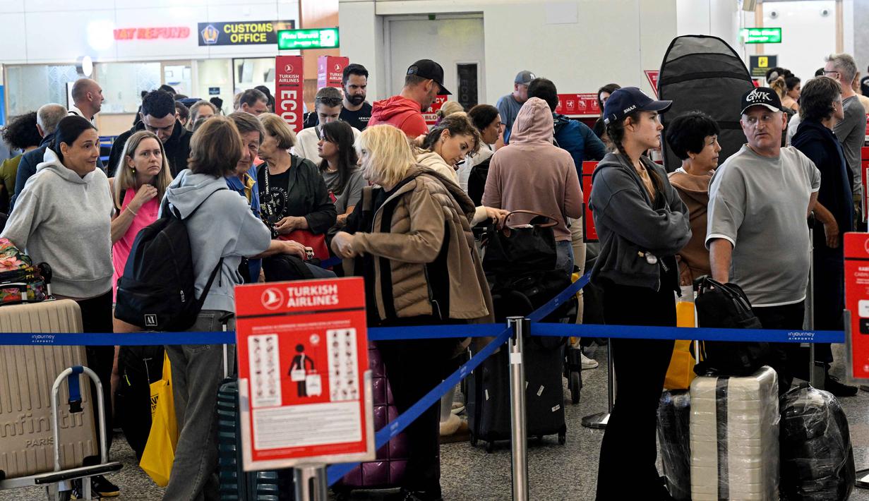 Pembatalan penerbangan rute Timur Tengah juga terjadi di Bandara Internasional Soekarno-Hatta, Tangerang, Banten. Tampak dalam foto, para penumpang menunggu di tengah gangguan penerbangan akibat serangan Israel-Amerika Serikat terhadap Iran, di Bandara Internasional I Gusti Ngurah Rai, Bali, pada Senin 2 Maret 2026. (SONNY TUMBELAKA/AFP)
