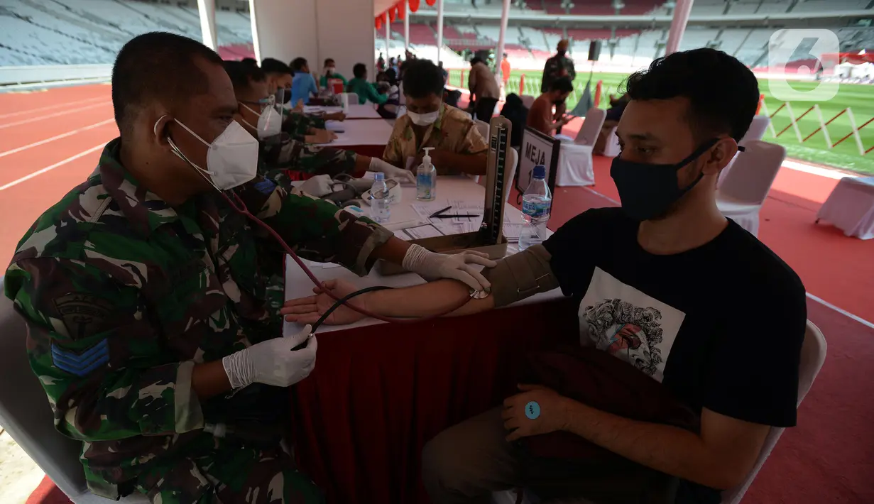 Aparat TNI memeriksa kondisi warga saat vaksinasi COVID-19 gratis di Stadion Gelora Bung Karno (GBK), Jakarta, Sabtu (26/6/2021). Vaksinasi dilakukan secara massal bagi warga ber-KTP DKI Jakarta. (merdeka.com/Imam Buhori)