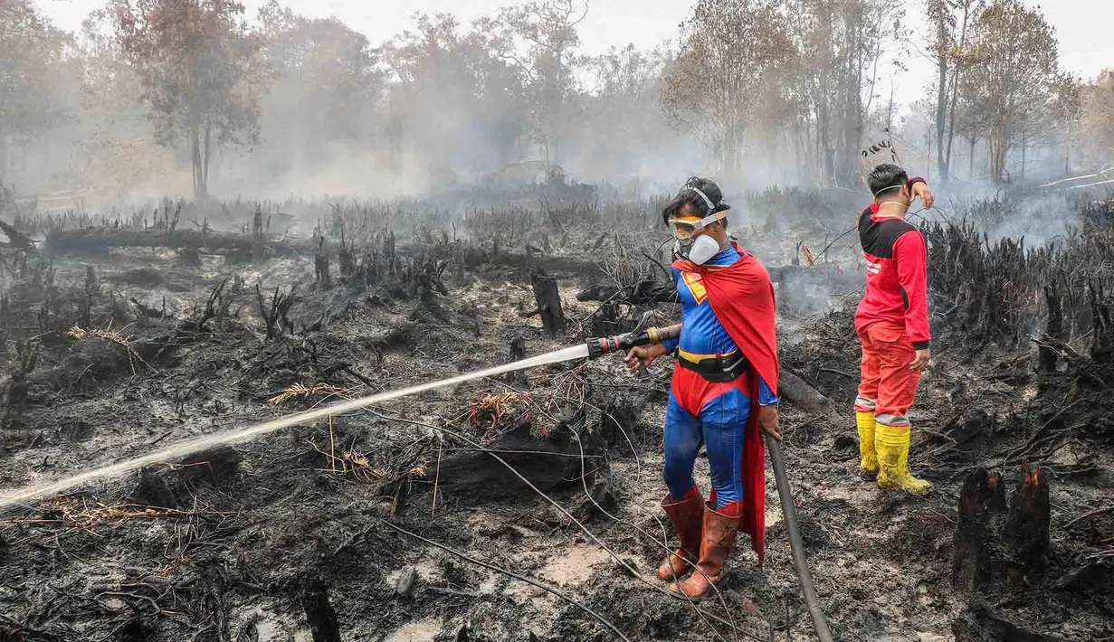 Pelajar bernama Rudiansyah dengan mengenakan kostum Superman membantu memadamkan kebakaran hutan dan lahan di Petuk Katimpun, Palangkaraya, Kalimantan Tengah, 17 Agustus 2026. (AFP/ Reina)