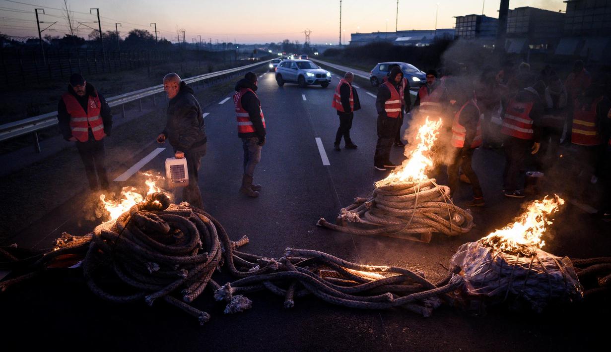 Anggota serikat pekerja memblokir jalan dalam sebuah aksi untuk menentang perombakan dana pensiun yang sangat tidak populer di Donges, Prancis Barat, Rabu (8/2/2023). Prancis bersiap menghadapi pemogokan baru dan demonstrasi massal menentang proposal Presiden Prancis untuk mereformasi pensiun Prancis, termasuk menaikkan usia pensiun dari 62 menjadi 64 tahun. (LOIC VENANCE/AFP)
