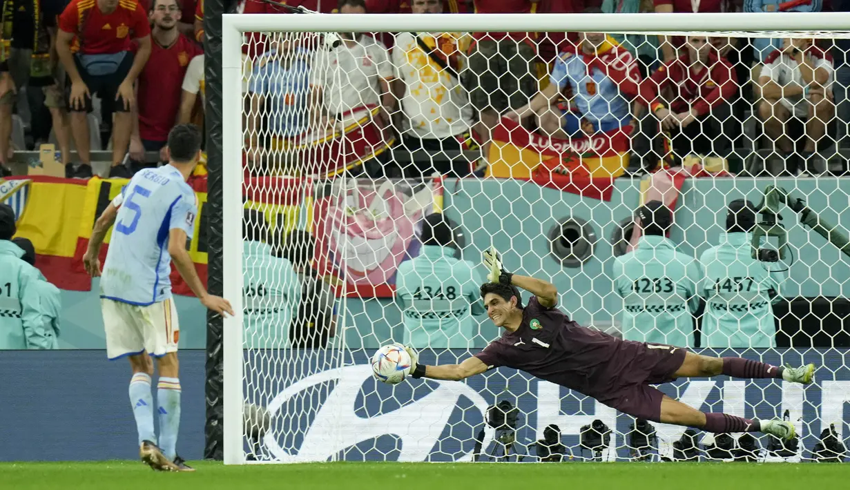 Kiper Maroko Yassine Bounou menghentikan tembakan penalti gelandang Spanyol Sergio Busquets dalam perpanjangan waktu pada babak 16 besar Piala Dunia 2022 di Education City Stadium, Al Rayyan, Rabu (6/12/2022) dini hari WIB. Singa Atlas menjadi tim Afrika keempat yang mencapai babak 8 besar pesta sepak bola termegah sejagad tersebut. (AP Photo/Francisco Seco)