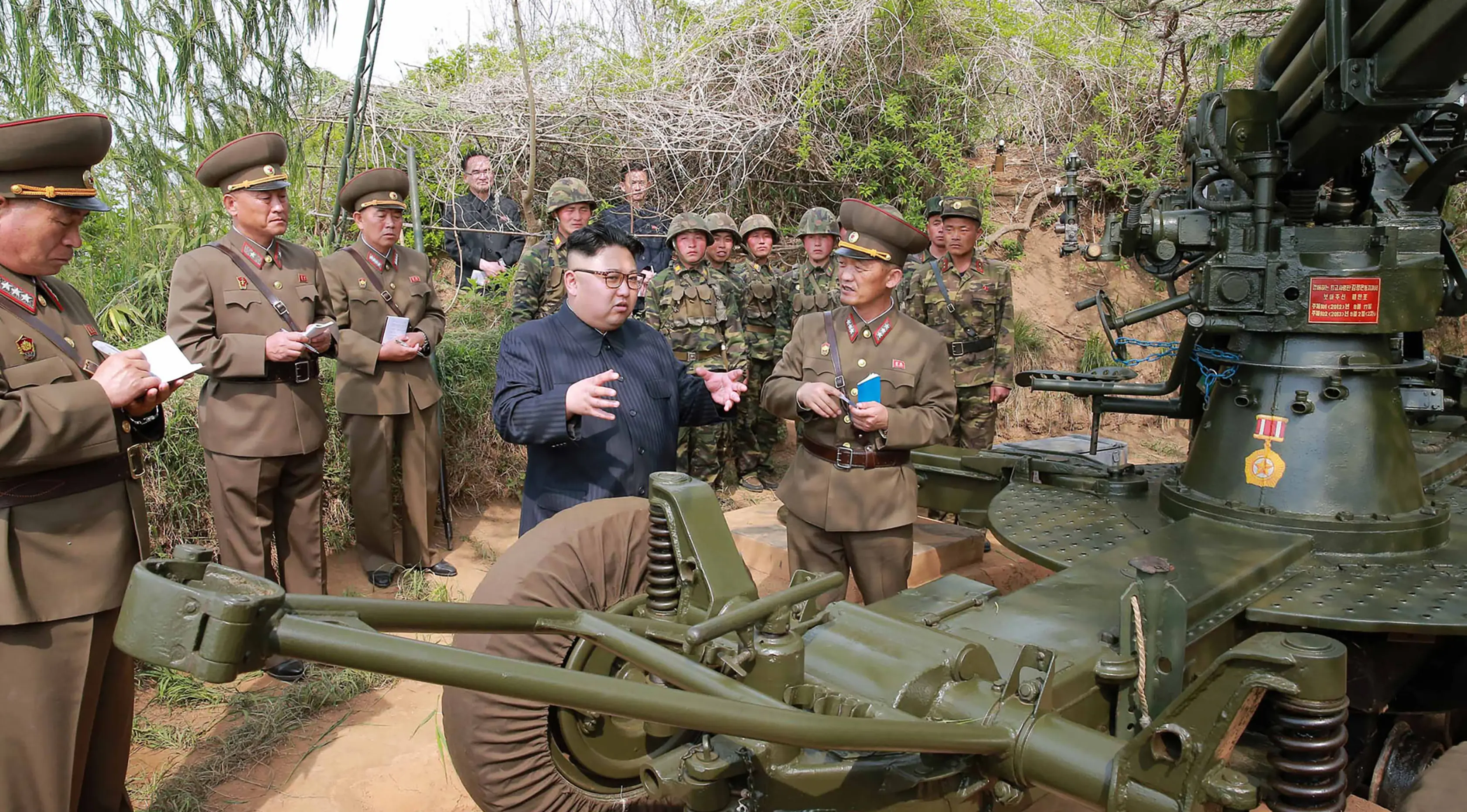Kim Jong-un berbincang dengan pejabat tentaranya saat memeriksa detasemen pertahanan di Pulau Jangjae dan Mu Islet, Korea Utara (5/5). Korut diketahui menempatkan sejumlah peluncur roket dan artileri di dua pulau kecil tersebut. (STR / KCNA VIA KNS / AFP)