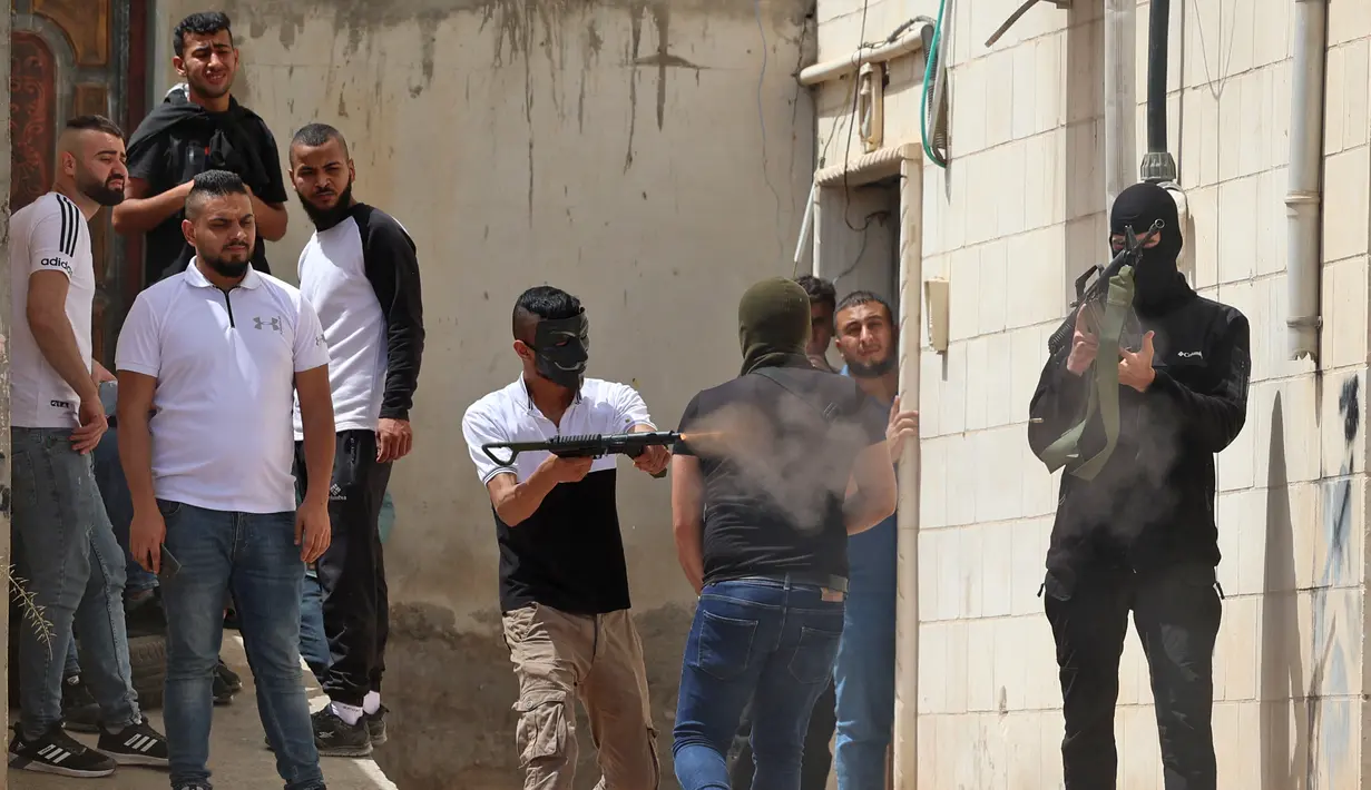 Seorang pria Palestina bertopeng menembakkan senjata otomatis selama bentrokan dengan pasukan keamanan Israel di kota Jenin di Tepi Barat pada 13 Mei 2022. Seorang warga Palestina terluka oleh tembakan Israel selama operasi di kota Jenin di Tepi Barat yang diduduki utara, kantor berita Palestina kata Wafa. (AFP/JAAFAR ASHTIYEH)