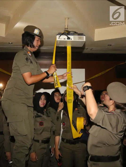 Petugas Satpol PP wanita memasang garis polisi Pamong Praja di Sense Karaoke di Mangga Dua Square, Jakarta, Kamis (19/4). Pemprov DKI Jakarta resmi menutup Sense Karaoke karena melanggar peraturan. (Liputan6.com/Arya Manggala)