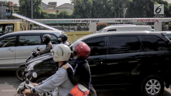 Pengendara melintasi dekat coret-coretan di sekitar Gedung DPR/MPR RI, Jakarta, Selasa (24/9/2019). Demonstrasi mahasiswa dari berbagai kampus yang menolak pengesahan RUU Kitab Undang-Undang Hukum Pidana(KUHP) tercoreng oleh aksi coret-coretan. (Liputan6.com/Faizal Fanani)