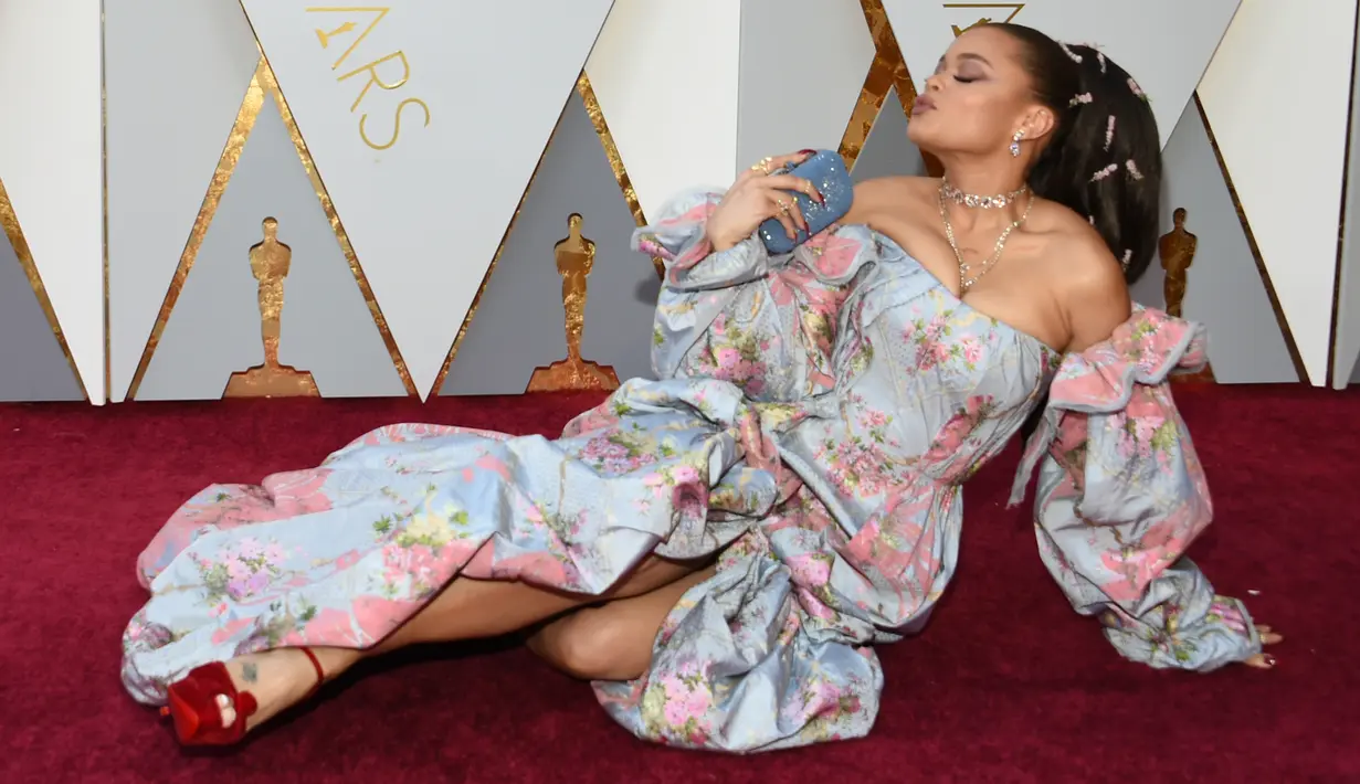 Pose rebahan penyanyi Andra Day di karpet merah saat menghadiri penghargaan Piala Oscars 2018 di Dolby Theatre, Los Angeles, Minggu (4/3). Pose Andra Day ini menjadi momen unik dalam sejarah Academy Awards yang memasuki tahun ke-90. (VALERIE MACON / AFP)