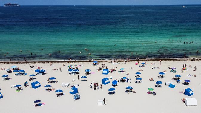 Pandangan udara menunjukkan orang-orang berada di atas pasir Miami Beach di Florida, Rabu (10/6/2020). Pantai Miami dibuka hari ini untuk pertama kalinya setelah hampir tiga bulan ditutup guna menekan jumlah penyebaran corona Covid-19. (CHANDAN KHANNA / AFP)