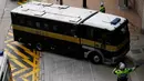 Seorang polisi mengarahkan mobil penjara yang membawa Rurik Jutting ke Pengadilan Tinggi di Hong Kong, Selasa (25/10). Jutting didakwa atas pembunuhan WNI di Hong Kong, SM dari Jawa Tengah dan JL dari Sulawesi pada tahun 2014. (Reuters/Bobby Yip)
