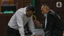 Terdakwa musisi I gede Ari Astina atau Jerinx berbincang dengan kausa hukumnya saat mengikuti sidang tuntutan di PN Jakarta Pusat, Jakarta, Jumat (18/2/2022). Jerinx dituntut dua tahun penjara dan denda Rp50 juta subsider dua bulan kurungan. (Liputan6.com/Herman Zakharia)