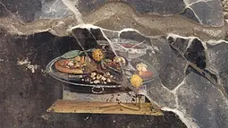 Para arkeolog di Pompeii mengatakan pada hari Selasa bahwa mereka telah menemukan lukisan dinding kuno yang menggambarkan cikal bakal pizza di masa kini, namun tanpa keju dan tomat. (Handout / Parco Archeologico di Pompei press office / AFP)