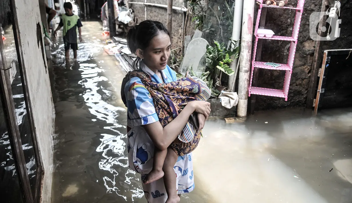 Warga menggendong anaknya saat melintasi banjir di permukiman warga di kawasan Kemang Timur XI, Jakarta Selatan, Minggu (21/2/2021). Ketinggian air mencapai sepinggang orang dewasa. (merdeka.com/Iqbal S. Nugroho)