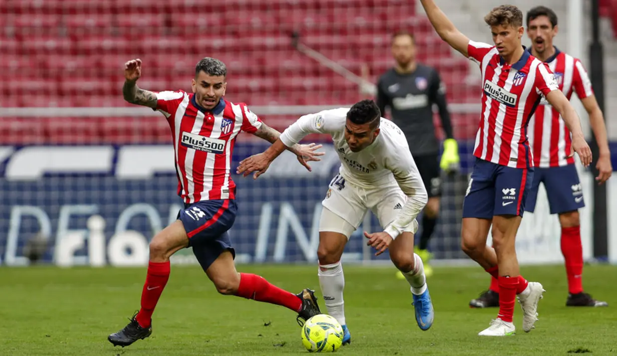 Pemain Atletico Madrid Angel Correa (kiri) memperebutkan bola dengan pemain Real Madrid Casemiro pada pertandingan Liga Spanyol di Stadion Wanda Metropolitano, Madrid, Spanyol, Minggu (7/3/2021). Pertandingan berakhir dengan skor 1-1. (AP Photo/Manu Fernandez)