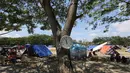 Sebuah jam dinding dipasang di pohon lapangan pengungsian Masjid Agung Daru Salam, Palu, Sulawesi Tengah, Jumat (5/10). Pemindahan dari tenda ke barak pengungsian untuk mempercepat penanganan pengungsi pascagempa. (Liputan6.com/Fery Pradolo)