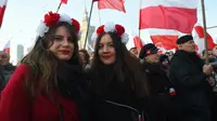 Orang-orang mengibarkan bendera nasional Polandia saat pawai untuk menandai Hari Kemerdekaan Nasional Polandia di Warsawa, Polandia, 11 November 2021. Hari Kemerdekaan Nasional Polandia dirayakan pada 11 November untuk memperingati ulang tahun Republik Polandia Kedua. (Adam Chelstowski/AFP)