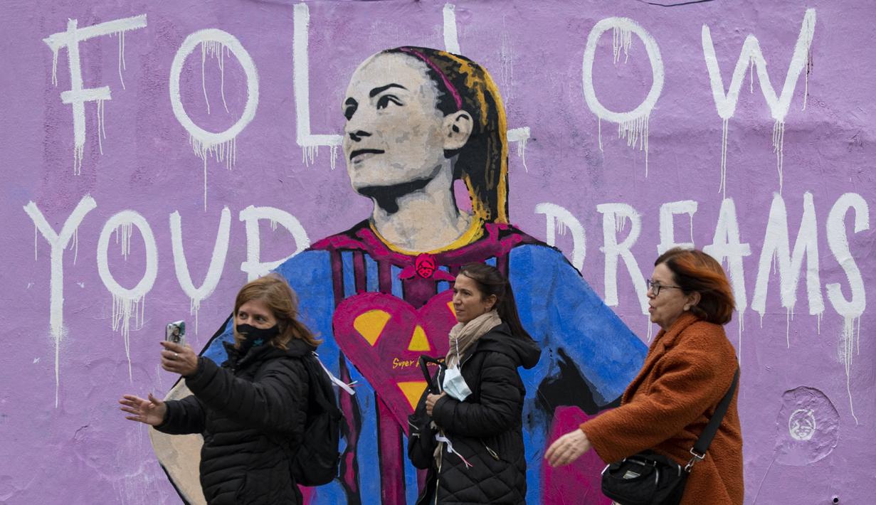 Sejumlah pejalan kaki melintasi mural bergambar Alexia Putellas yang dibuat oleh seniman Italia, TvBoy di Barcelona, 20 Maret 2022. (AFP/Josep Lago)