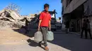 Seorang anak laki-laki berjalan membawa wadah air setelah mengisi ulang air dari sebuah tangki di kamp penampungan, Khan Yunis, Jalur Gaza Selatan pada 6 Juni 2026. (Bashar Taleb/AFP)