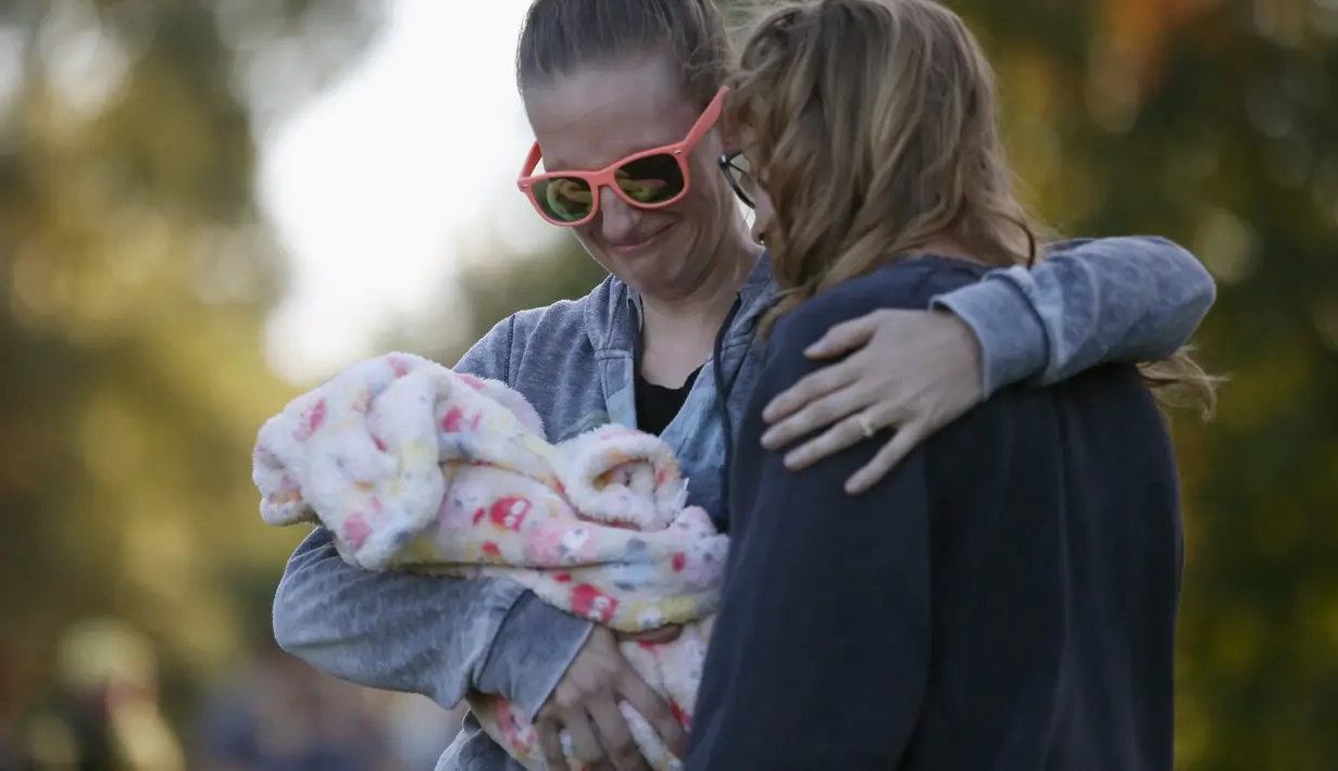 Dua wanita menangis melakukan aksi simpatik mengenang korban penembakan di Kampus Umpqua Community College di Roseburg, Sabtu (3/10/2015). Setidaknya 15 orang tewas dalam peristiwa tersebut. (REUTERS / Lucy Nicholson)