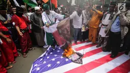 Pengunjuk rasa membakar bendera Amerika Serikat dan foto Donald Trump saat berunjuk rasa di depan Kedubes AS, Jakarta, Senin (11/12). Mereka menolak klaim sepihak Presiden Donald Trump soal Yerusalem sebagai Ibu Kota Israel. (Liputan6.com/Faizal Fanani)