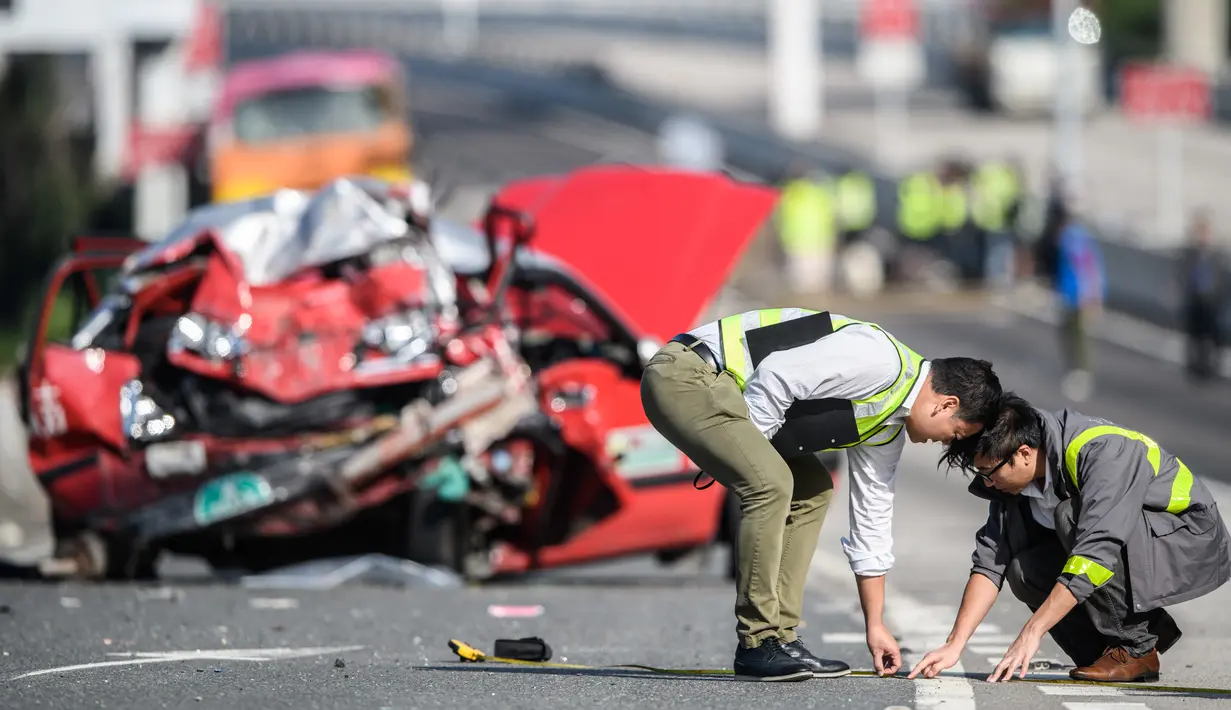 Polisi mengukur jalanan setelah kejadian kecelakaan bus dan taksi di Hong Kong (30/11). Lima orang tewas dan 32 luka-luka setelah akibat kecelakaan tersebut. (AFP Photo/Anthony Wallace)