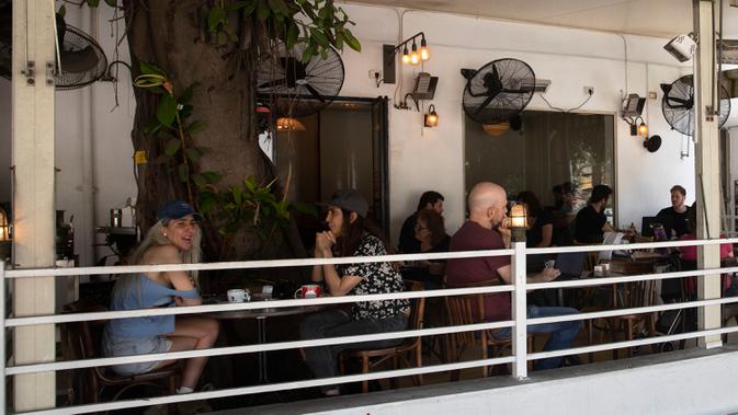 Pengunjung makan di luar di sebuah restoran di Tel Aviv, Israel pada Rabu (27/5/2020). Setelah lebih dari dua bulan ditutup untuk membendung penularan virus corona, restoran hingga kafe di Israel diizinkan dibuka kembali hari Rabu, 27 Mei. (AP Photo/Sebastian Scheiner)