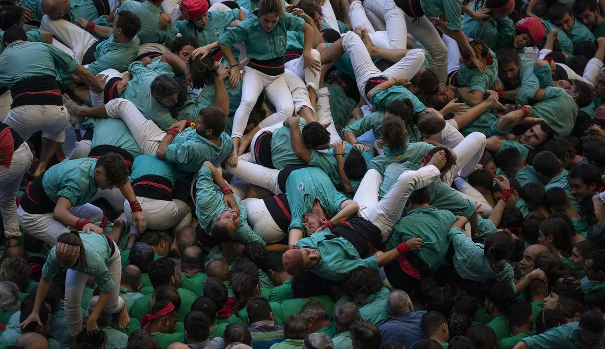 Anggota "Castellers de Vilafranca" jatuh saat mereka mencoba menyelesaikan menara manusia mereka selama Kompetisi Menara Manusia ke-28 di Tarragona, Spanyol, Minggu (2/10/2022). Orang-orang yang membuat menara manusia dengan teknik tersendiri untuk berkompetisi dikenal sebagai 'colles'. (AP Photo/Joan Mateu Parra)