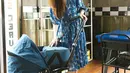 Walaupun membawa stroller bayi, tampilan ibu muda ala Yasmine Wildblood ini bisa jadi inspirasi. Ia tampak mengenakan midi dress yang flowy berwarna biru dengan motif hewan, bak remaja berpenampilan playful. Foto: Instagram.