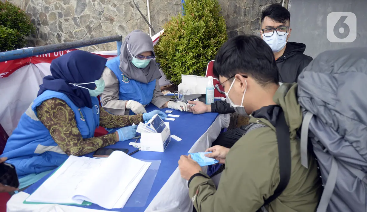 Petugas medis mengambil sempel rapid test warga di Pos PAM Pamulang Square, Tangerang Selatan, Banten, Jumat (25/12/2020). Rapid test gratis yang digelar Polres Tangerang Selatan tersebut bertujuan untuk mencegah penularan COVID-19 saat Natal dan Tahun Baru. (merdeka.com/Dwi Narwoko)