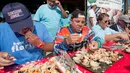 Para peserta beradu cepat memakan daging kepiting batu dalam kontes Key Fisheries Stone Crab Eating di Marathon, Florida, Sabtu (10/11). Mereka harus memecahkan cangkang 25 kepiting batu lalu memakan dagingnya. (Andy Newman/Florida Keys News Bureau/AFP)