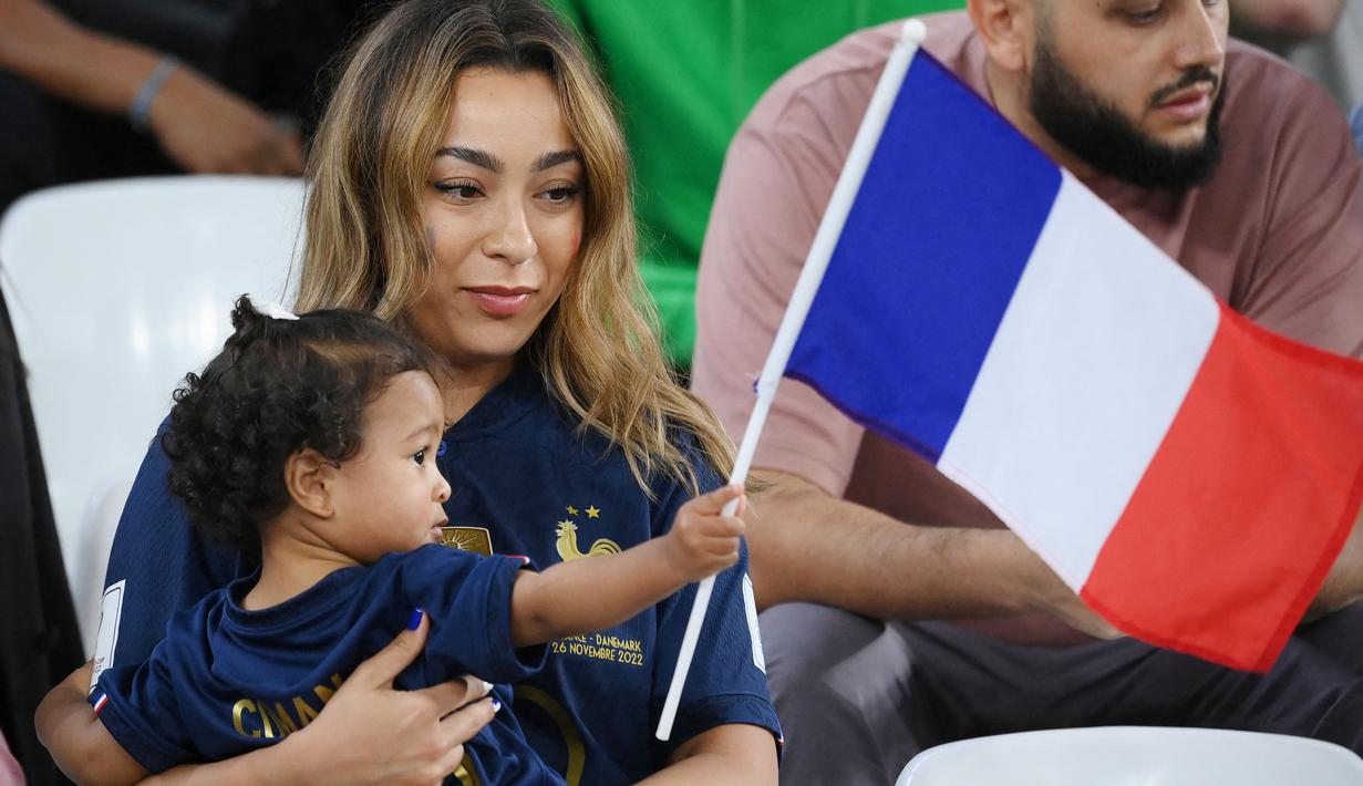 Istri Kingsley Coman, Sabrajna Duvad, bersama anaknya hadir langsung memberikan dukungan saat Timnas Prancis berhadapan dengan Tunisia di Stadion Education City, Al-Rayyan (30/11/2022). (AFP/Franck Fife)