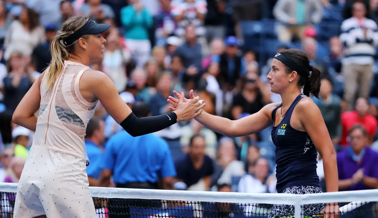 Petenis Rusia, Maria Sharapova bersalaman dengan Anastasija Sevastova dari Latvia usai pertandingan babak keempat grand slam AS Terbuka 2017 di New York (3/9). Sevastova menang 5-7, 6-4, 6-2 atas Sharapova. (Richard Heathcote/Getty Images/AFP)