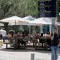 Orang-orang duduk di luar sebuah kafe di kota pantai Mediterania Israel di Tel Aviv, Rabu (27/5/2020). Setelah lebih dari dua bulan, Israel pertama kalinya mengizinkan restoran hingga kafe dibuka kembali usai pelonggaran pembatasan yang diberlakukan untuk mencegah Covid-19. (JACK GUEZ/AFP)